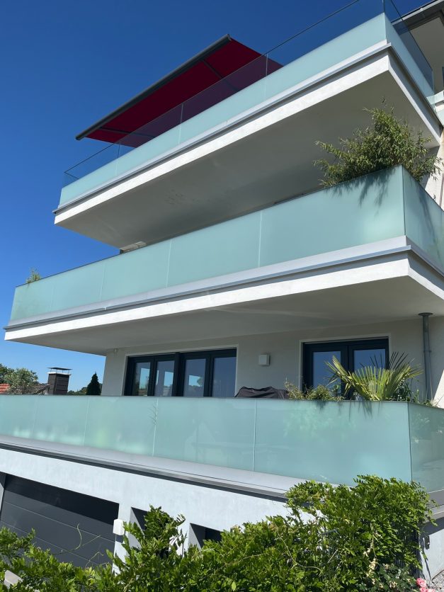Mehrgeschossiges Wohnhaus mit umlaufenden Balkonen und Glasbrüstungen